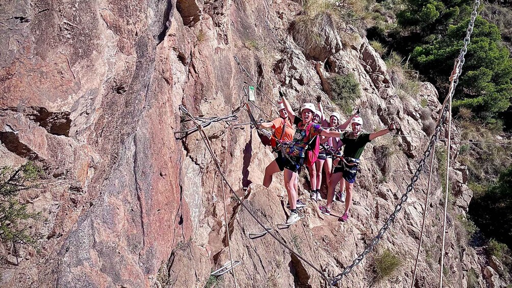A group of people rappelling down a rocky cliff. 5