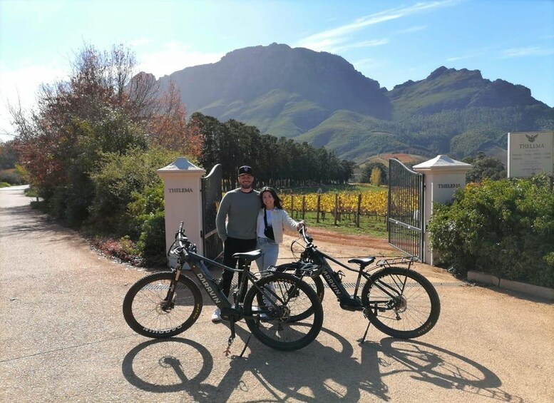 Viñedo con montañas al fondo, una puerta con la inscripción 'THELEMA' y dos bicicletas. 5