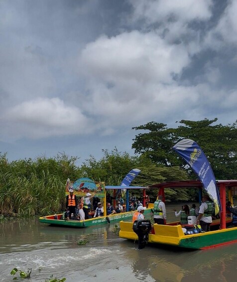 Un grupo de personas en un recorrido en barco, con un toldo y una bandera. 3