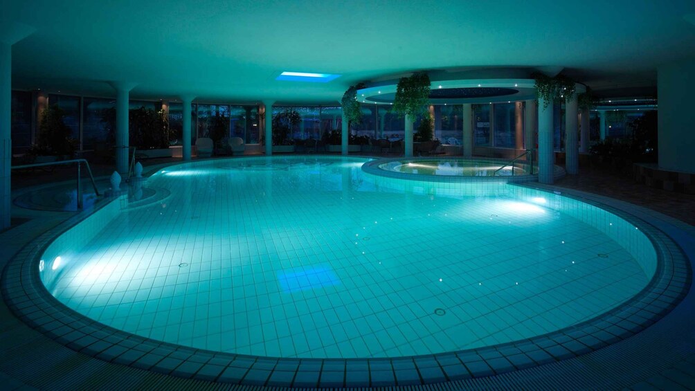 A large indoor swimming pool with a tiled floor and a central island. 5