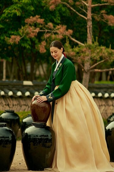 A person in traditional attire standing next to large black vases. 3