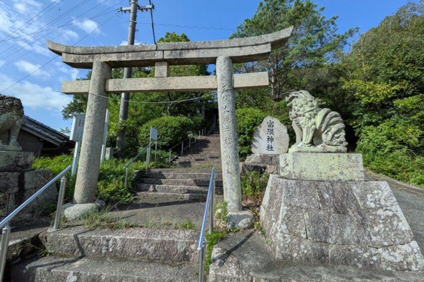 A stone staircase leading up to a torii gate with a lion statue at the base. 3