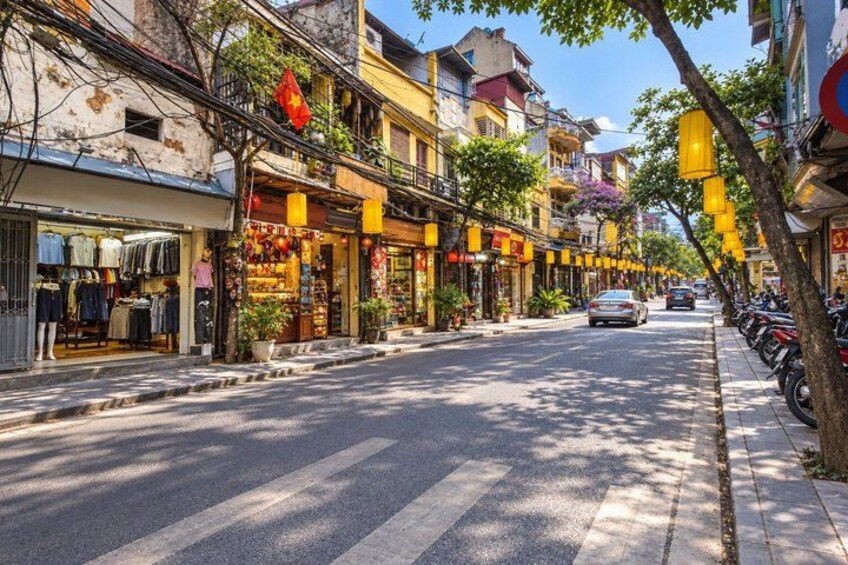 A street lined with shops, trees, and parked motorcycles. 2