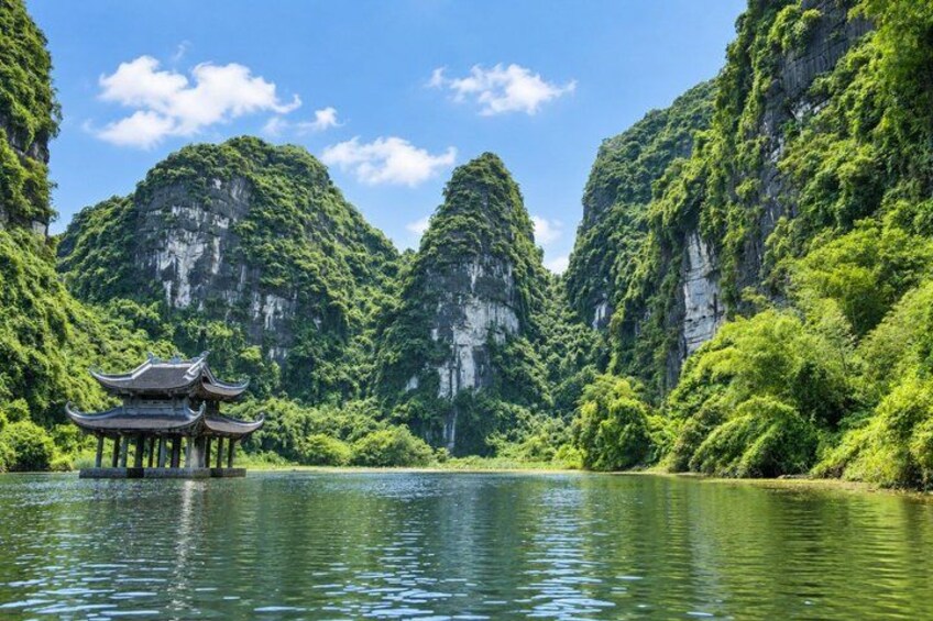 A traditional Chinese pavilion on a calm river surrounded by lush green mountains. 3