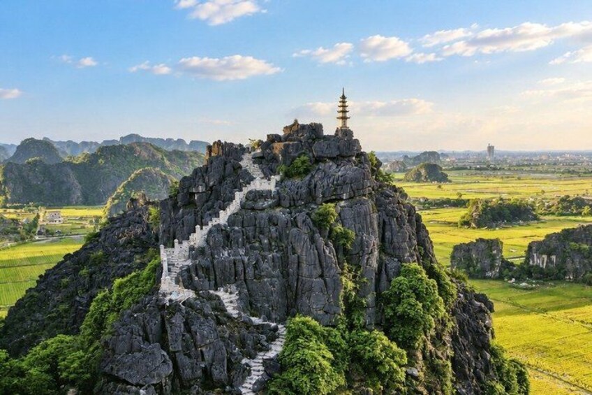 A temple on a rocky mountain peak with a staircase leading up to it. 4