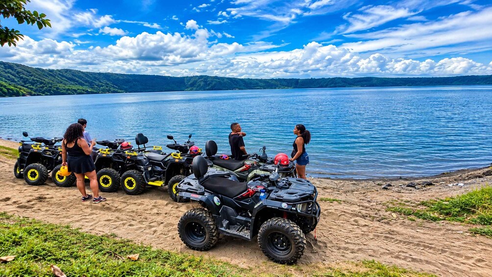 A group of people with ATVs by a lake. 1