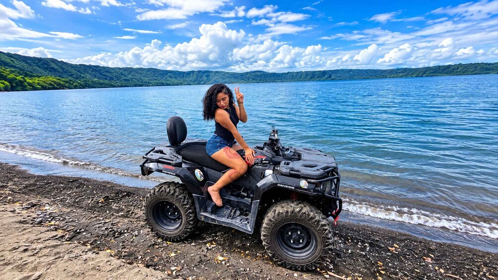 A person on a black ATV by a lake with a clear sky. 3