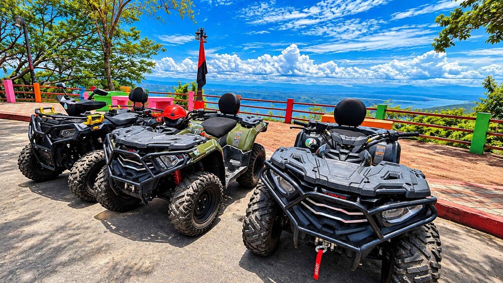 Four off-road vehicles parked on a paved area with a scenic view of mountains and a clear sky. 5