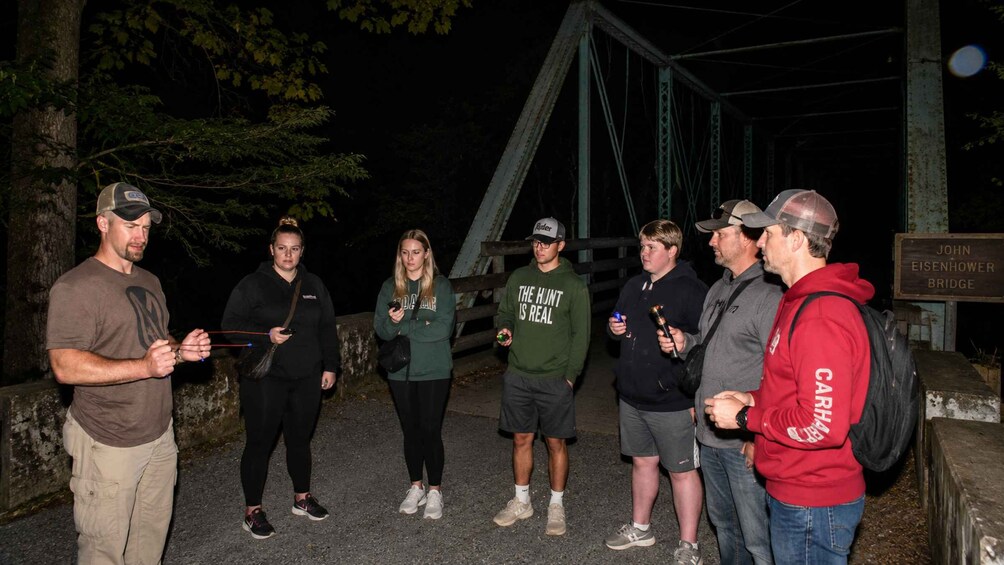 Un grupo de personas de pie sobre un puente de noche. 3