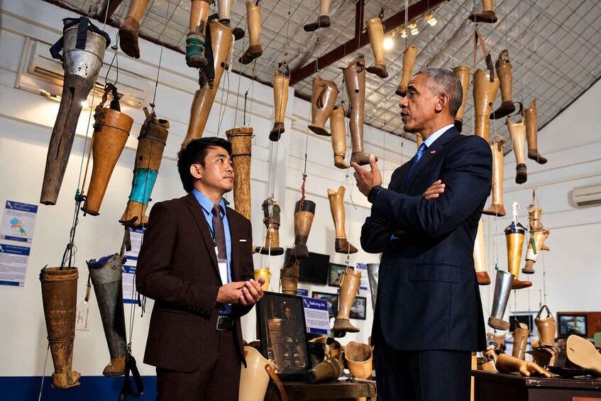Dos hombres en un museo con varios artefactos de madera colgando del techo. 5