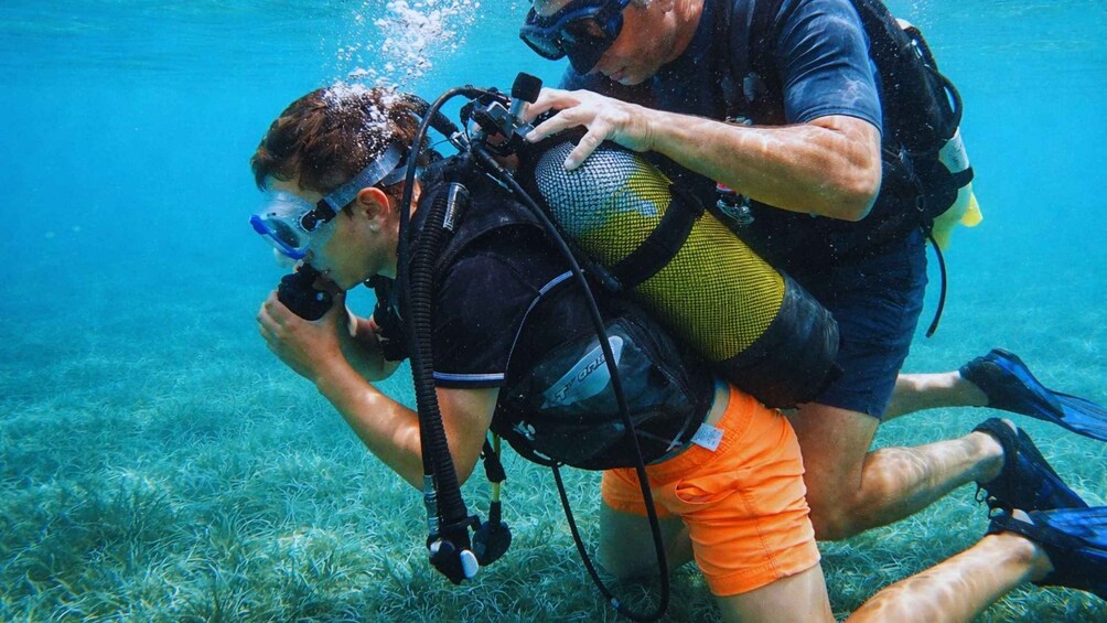 Two scuba divers underwater, one assisting the other. 4