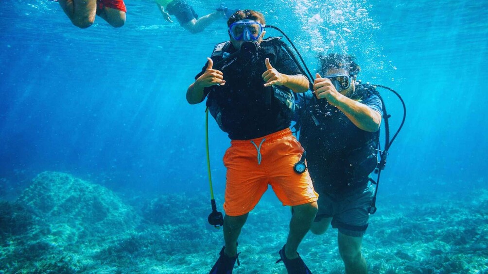 Two scuba divers underwater with one giving a thumbs-up. 3