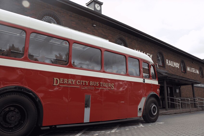 A red and white bus parked in front of a building with a clock tower and the words 'Railway Museum' on the side. 2