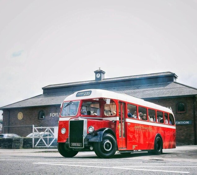 A red and white vintage bus with the number 235 parked in front of a building labeled 'FOYLANDS STATION'. 1