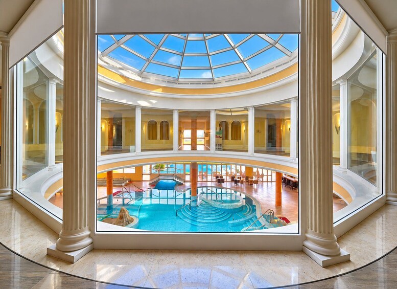 A grand atrium with a central pool, high ceilings, and classical architecture. 1