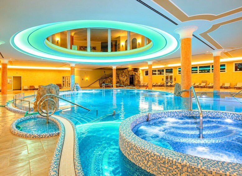 An indoor swimming pool with a hot tub, lounge chairs, and a circular viewing area. 4