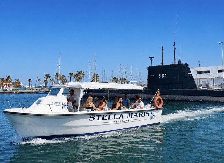 A white boat with 'STELLA MARIS SALINAS' written on it, moving on the water with people on board. 1