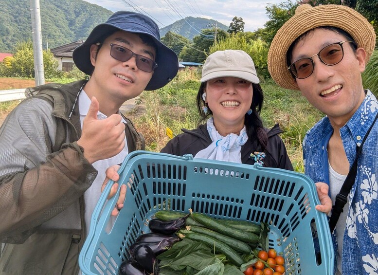 Three people holding a blue basket with vegetables. 1