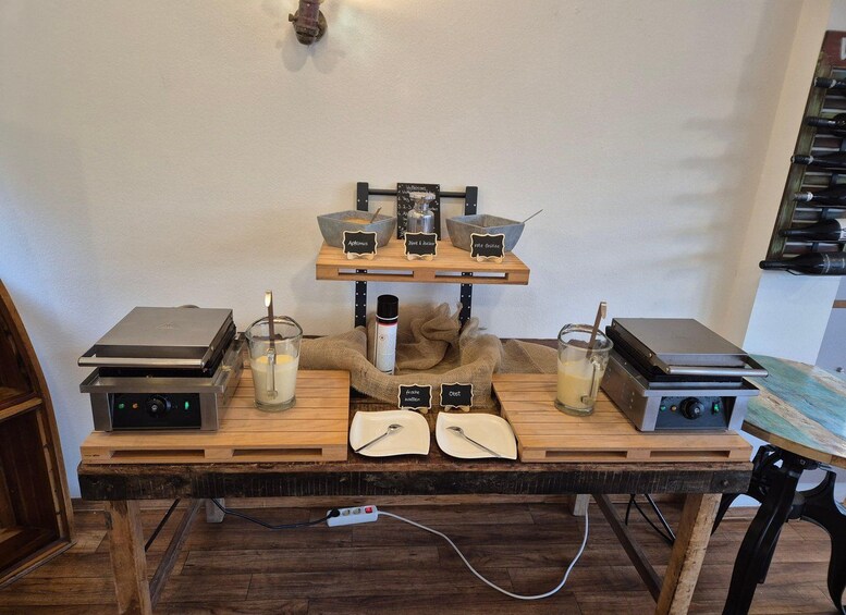 A wooden table with two coffee machines, a milk frother, and a coffee grinder. 3