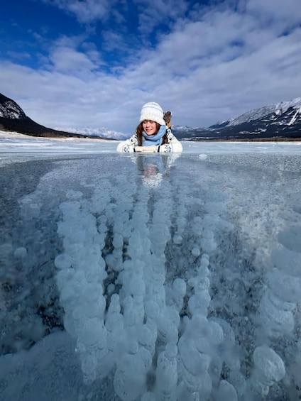 A person standing on a frozen lake with mountains in the background. 1