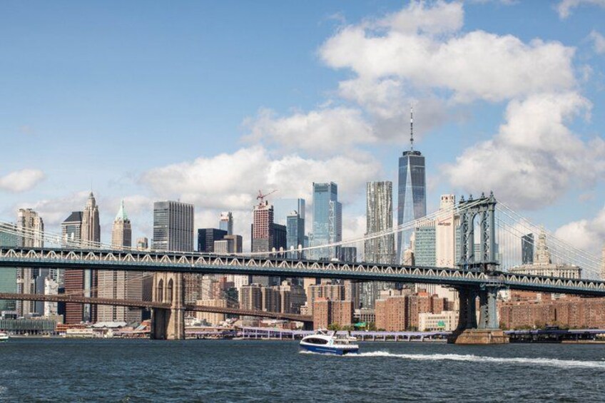 A city skyline with a prominent bridge, a boat on the water, and several skyscrapers. 1