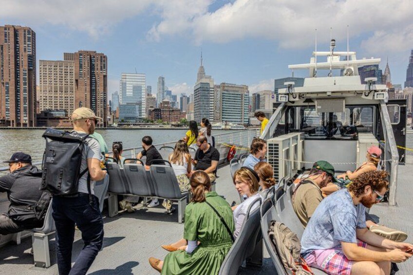 A boat tour with passengers, a city skyline in the background, and a river. 4