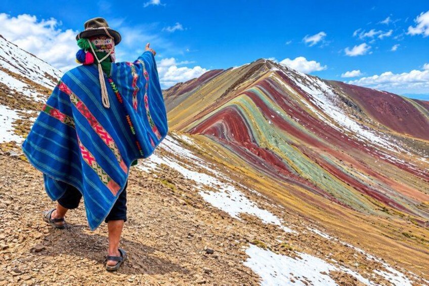 A person walking on a rocky path with colorful mountain terrain in the background. 3