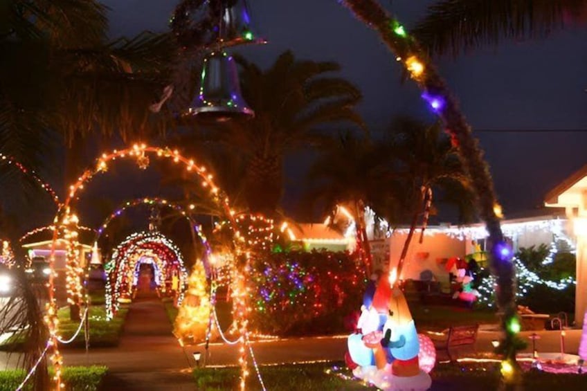 A house decorated with colorful lights, palm trees, and a bell. 1