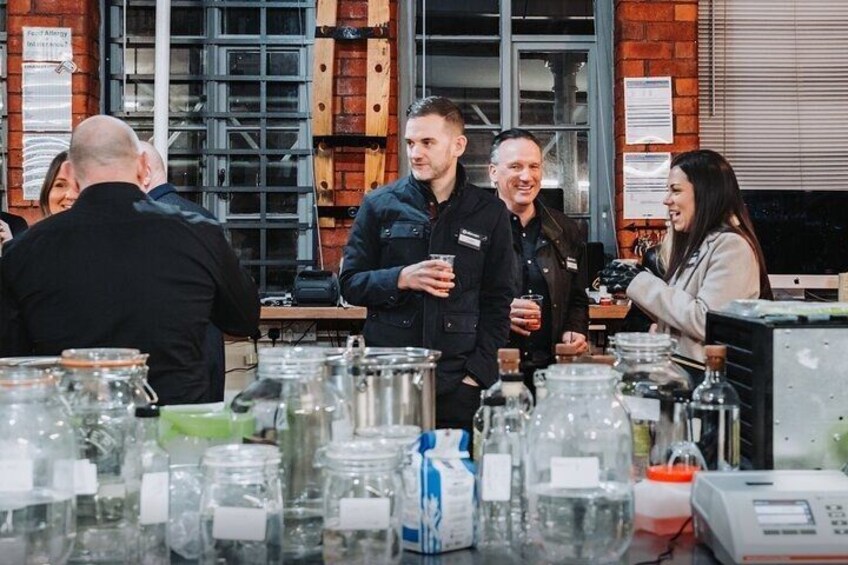 People at a table with glass containers and a machine. 3
