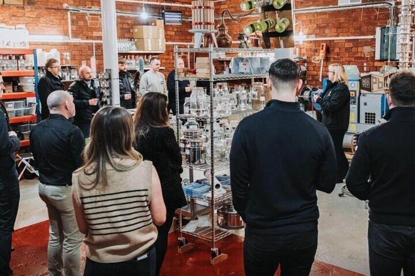 A group of people in an industrial setting with metal shelves and equipment. 2