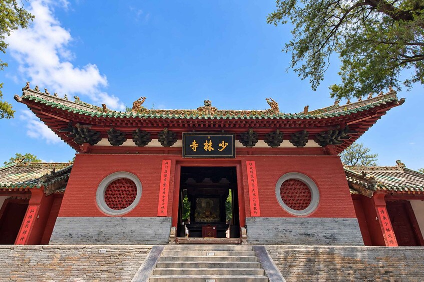 A traditional Chinese gate with ornate roof and red walls, featuring circular windows and a sign with Chinese characters. 2