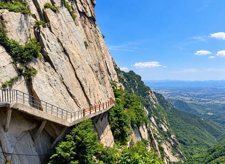 A concrete bridge with metal railings spanning a steep cliff. 5