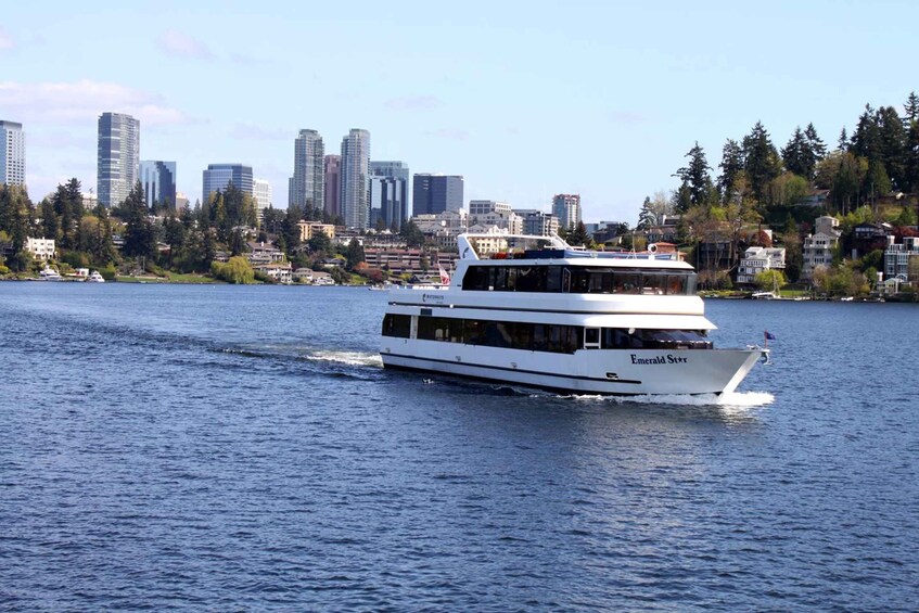 A white boat named 'Emerald Star' on a body of water with a city skyline in the background. 3