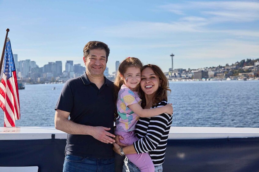 A family of three on a boat with a city skyline and water in the background. 1