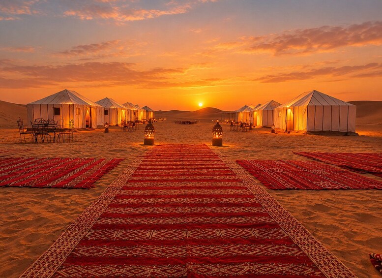 Un paysage désertique avec des yourtes et un tapis rouge menant à un coucher de soleil. 1