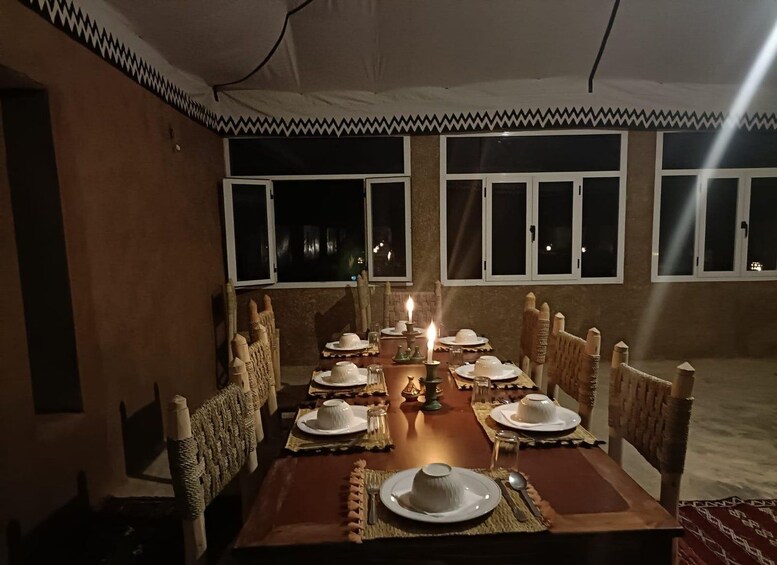 Une table à manger dressée pour six personnes, avec des bougies, des assiettes et un élément décoratif central. 4