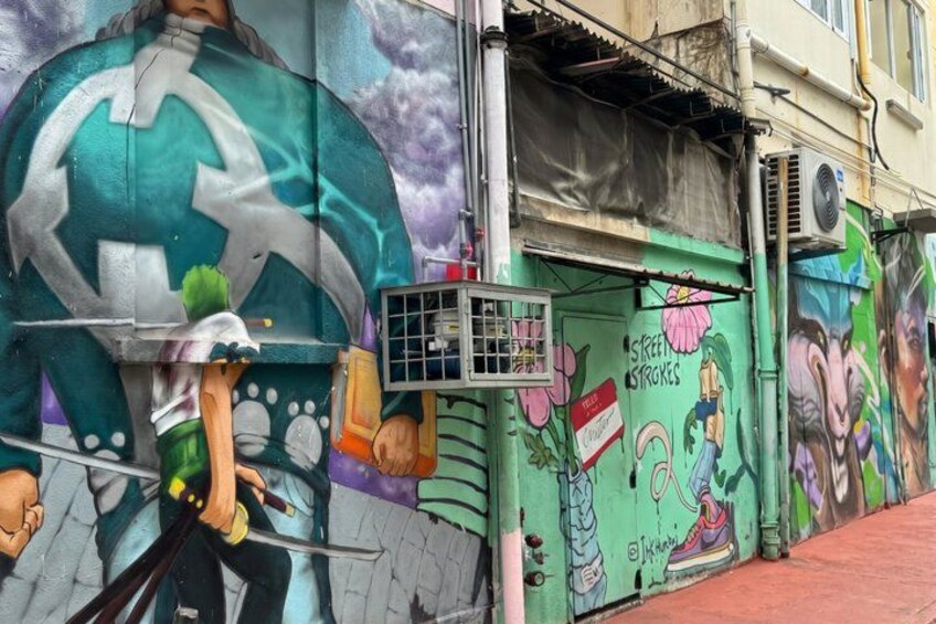 A colorful mural with a large circular design, a small window, and a sign that reads 'Street Strokes.' 3