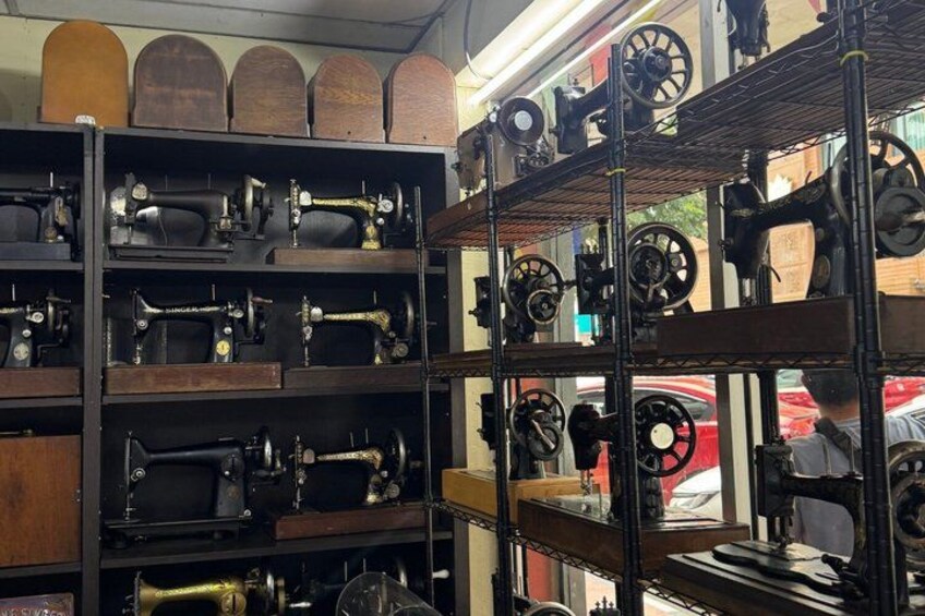 A collection of antique sewing machines on shelves. 2