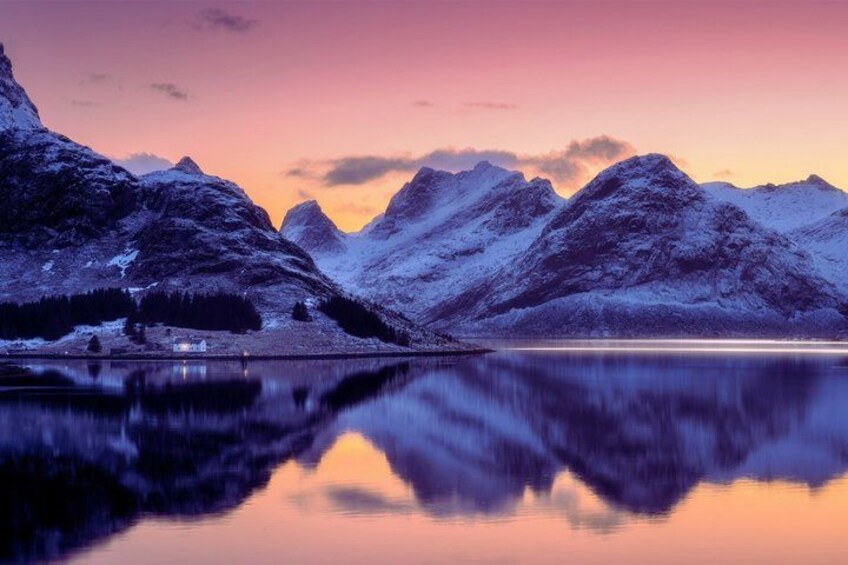 A mountain landscape with a lake reflecting the peaks, a clear sky, and a small cabin by the shore. 1