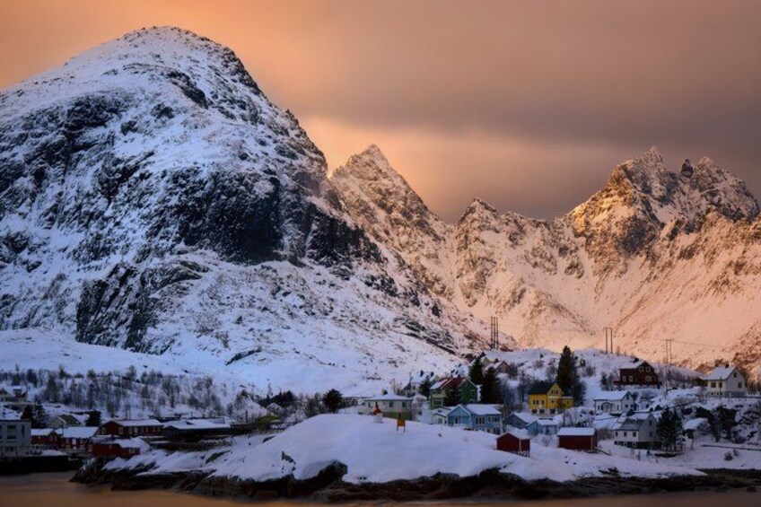 A snow-covered mountain range with a small village at its base. 2