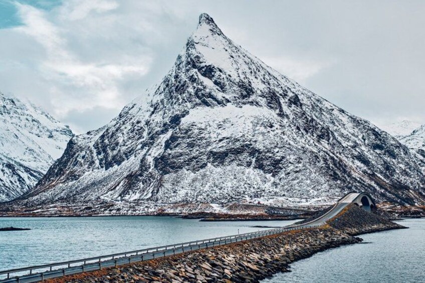 A snow-covered mountain with a bridge over a body of water. 5