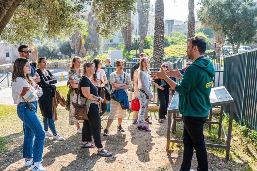 A group of people standing outdoors, engaged in a discussion with a guide. 2