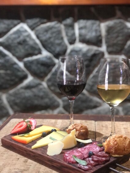A charcuterie board with various cheeses, fruits, and meats, accompanied by two wine glasses. 4