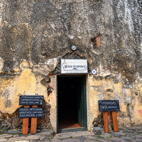 A rustic building entrance with signs advertising local food and wine. 3