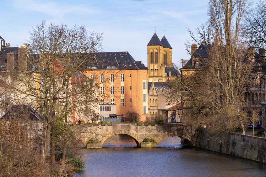 A historic building with a tower, a bridge over a river, and leafless trees. 5