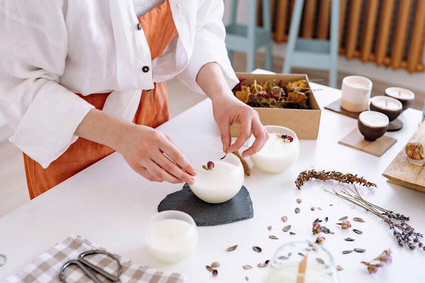 Una persona preparando un plato con un tazón de líquido blanco sobre una tabla de pizarra, rodeada de diversas hierbas y especias. 5