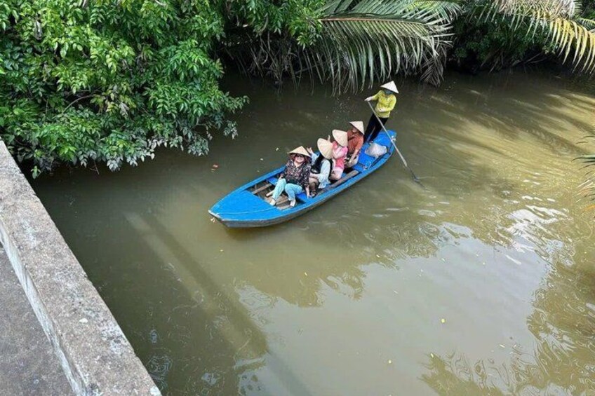 A blue boat with passengers on a river surrounded by greenery. 3
