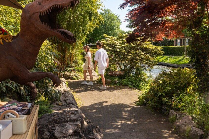 A dinosaur statue, a pathway, and a pond. 3