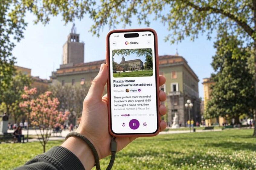 A hand holding a smartphone displaying an article about Piazza Roma. 1