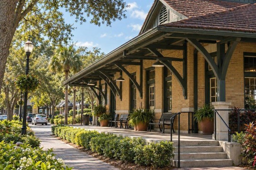 A covered outdoor area with benches, potted plants, and a brick building. 3